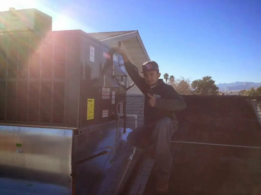 HVAC technician performing Boiler Repair on a rooftop unit in Gonzales